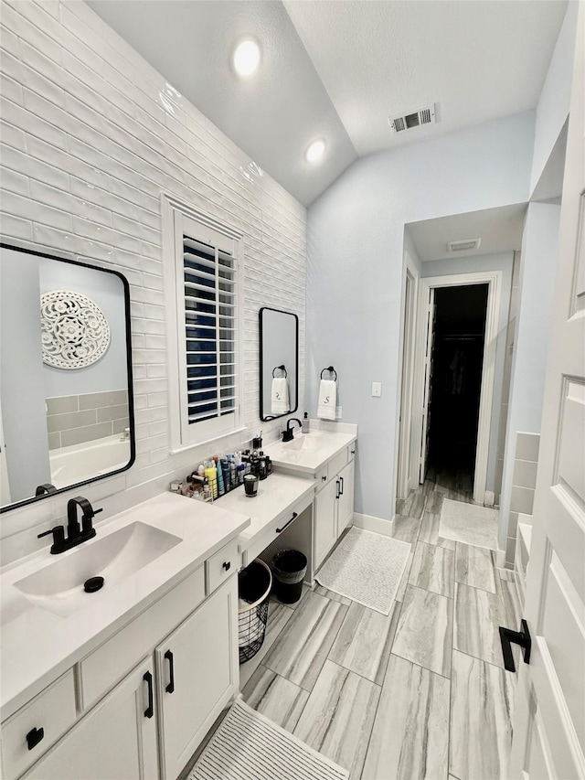 2312 Camp St, Aubrey, TX 76227 - bathroom with vaulted ceiling, vanity, a tub, recessed lighting, and a walk in closet