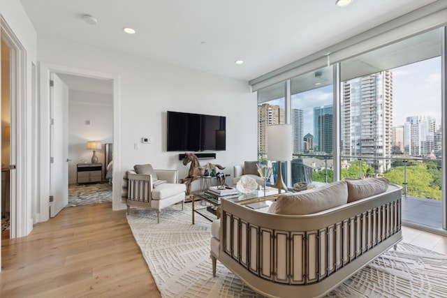 living area with light wood-style floors, a healthy amount of sunlight, a wall of windows, and recessed lighting