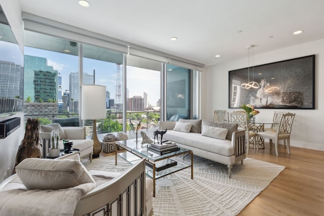 living area with a view of city, a wall of windows, a chandelier, recessed lighting, and wood finished floors