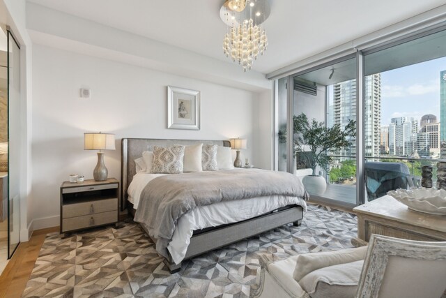 bedroom with baseboards, a chandelier, wood finished floors, access to outside, and expansive windows