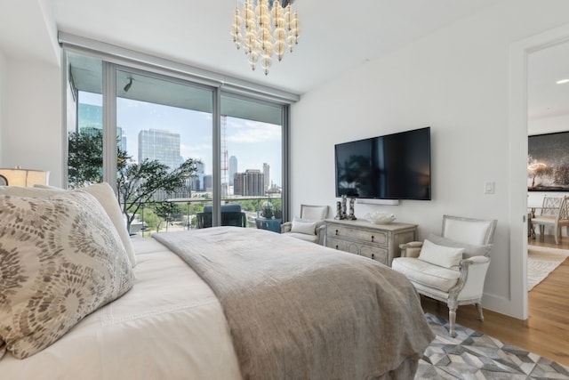 bedroom with access to outside, wood finished floors, a notable chandelier, and multiple windows