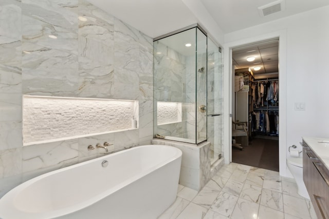 bathroom featuring visible vents, a freestanding bath, a spacious closet, a shower stall, and vanity
