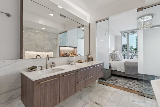 full bath featuring double vanity, marble finish floor, a sink, and connected bathroom