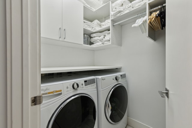 clothes washing area featuring cabinet space, washing machine and clothes dryer, and baseboards
