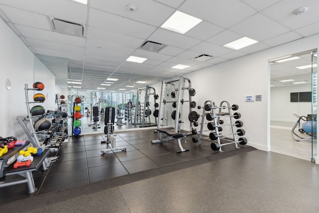 workout area with baseboards, a drop ceiling, and visible vents