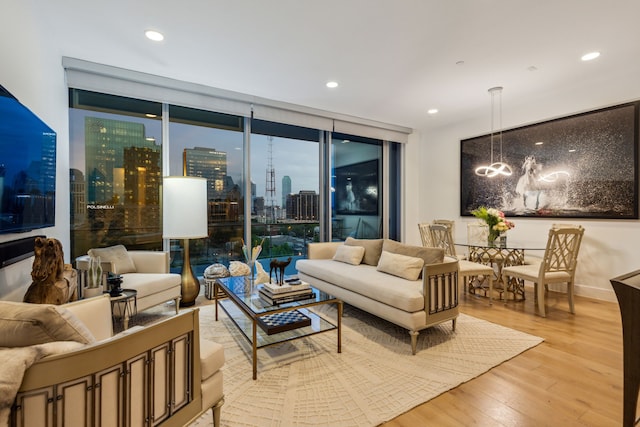 living room featuring an inviting chandelier, a view of city, recessed lighting, floor to ceiling windows, and light wood finished floors