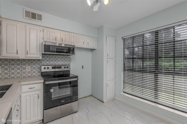 3100 Fairfield Ave Unit 8B, Shreveport, LA 71104 - kitchen featuring appliances with stainless steel finishes, light marble finish flooring, light countertops, backsplash, and white cabinets