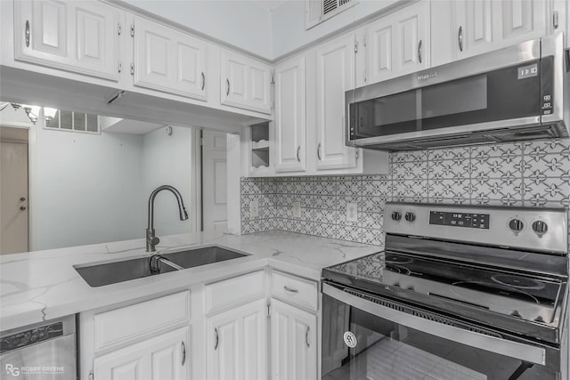 3100 Fairfield Ave Unit 8B, Shreveport, LA 71104 - kitchen featuring appliances with stainless steel finishes, a sink, white cabinets, backsplash, and light stone countertops