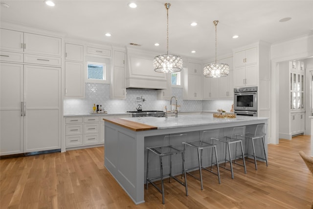 6946 Southridge Dr, Dallas, TX 75214 - kitchen with appliances with stainless steel finishes, white cabinetry, tasteful backsplash, a kitchen breakfast bar, and recessed lighting