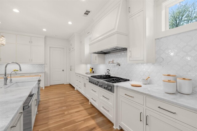 6946 Southridge Dr, Dallas, TX 75214 - kitchen with custom exhaust hood, stainless steel gas cooktop, white cabinetry, backsplash, and light wood-type flooring