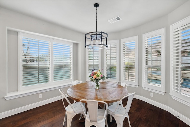 dining area with dark wood finished floors, baseboards, visible vents, and an inviting chandelier