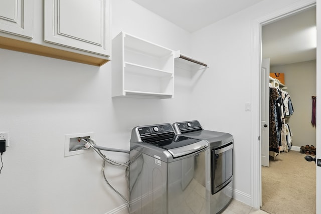 laundry area featuring light colored carpet, washer and dryer, cabinet space, and baseboards