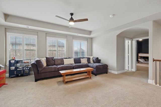 living room featuring visible vents, carpet, baseboards, ceiling fan, and arched walkways