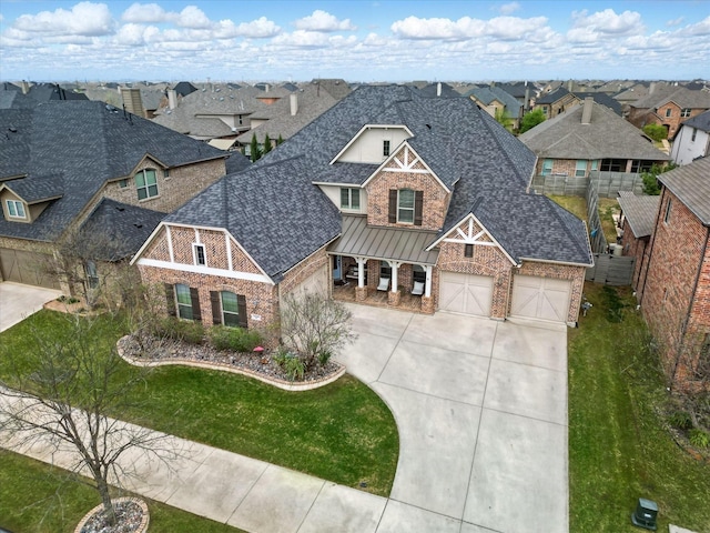 view of front facade with driveway, stone siding, roof with shingles, brick siding, and a residential view