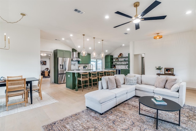 living area with lofted ceiling, recessed lighting, ceiling fan, light wood-style flooring, and visible vents