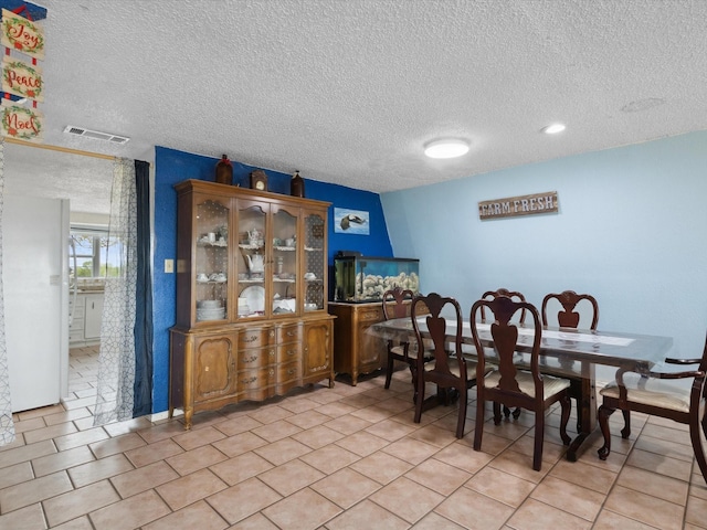 dining room with light tile patterned floors, a textured ceiling, and visible vents