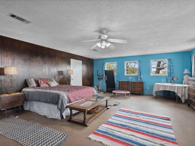 bedroom featuring visible vents, wooden walls, and a textured ceiling