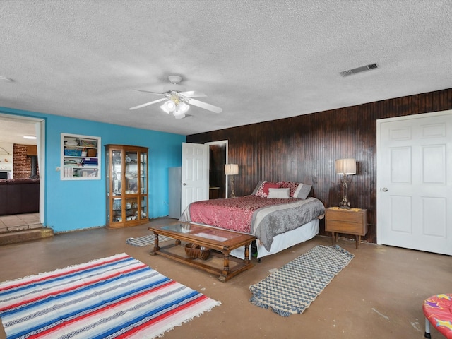 bedroom with visible vents, wooden walls, concrete floors, and a textured ceiling
