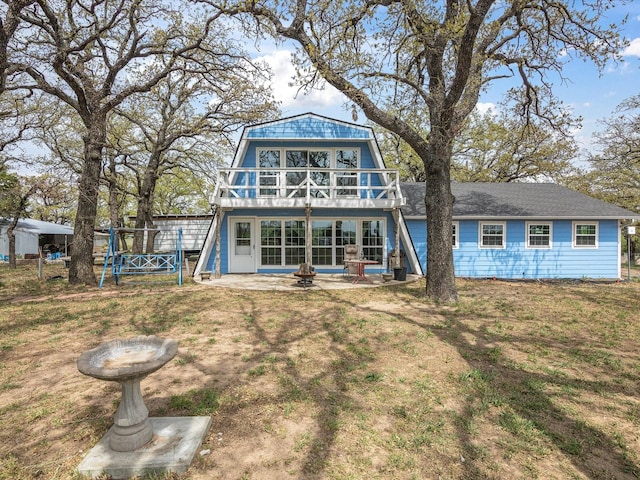 back of property featuring a gambrel roof, a wooden deck, and a lawn