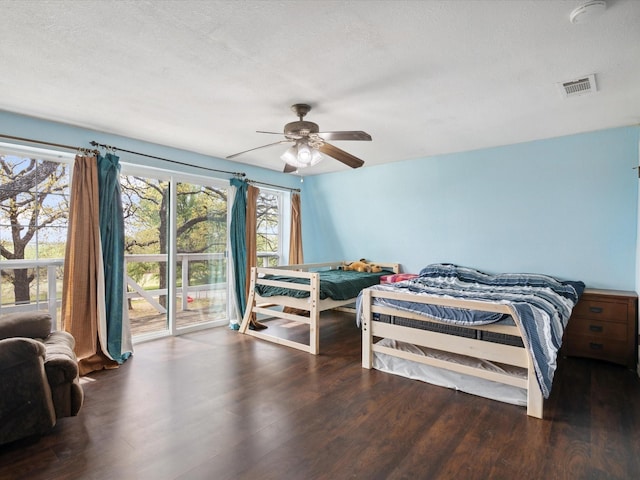 bedroom featuring a textured ceiling, ceiling fan, visible vents, and wood finished floors