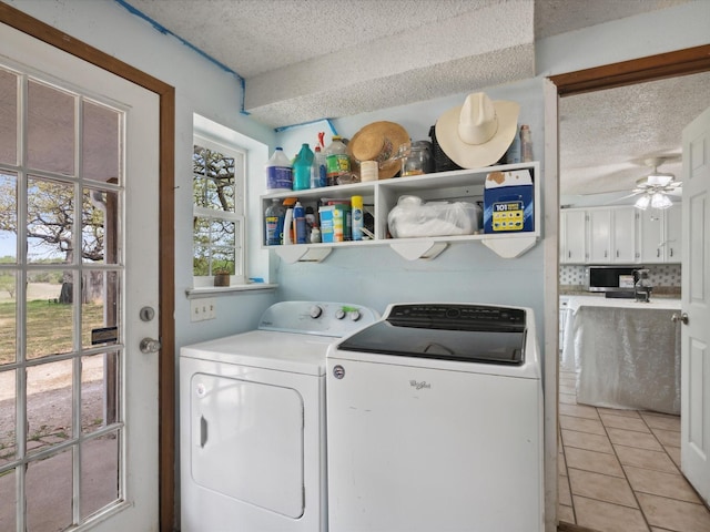 clothes washing area with light tile patterned flooring, a textured ceiling, laundry area, and washer and clothes dryer