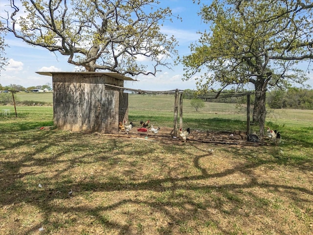 view of yard featuring fence, an outdoor structure, a rural view, and a storage shed