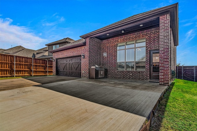 1596 Mannheim Dr, Rockwall, TX 75032 - rear view of house featuring concrete driveway, brick siding, an attached garage, and fence