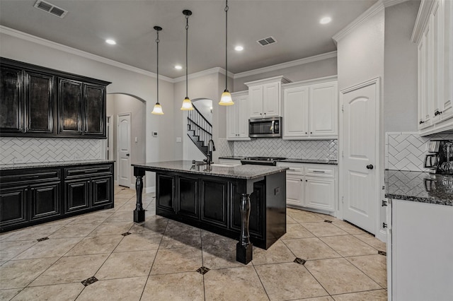 1596 Mannheim Dr, Rockwall, TX 75032 - kitchen featuring visible vents, arched walkways, dark cabinets, and stainless steel appliances