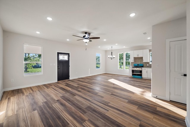 unfurnished living room featuring a chandelier, recessed lighting, ceiling fan, wood finished floors, and baseboards