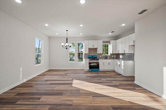 kitchen featuring stainless steel range with gas cooktop, a chandelier, a sink, white cabinets, and recessed lighting