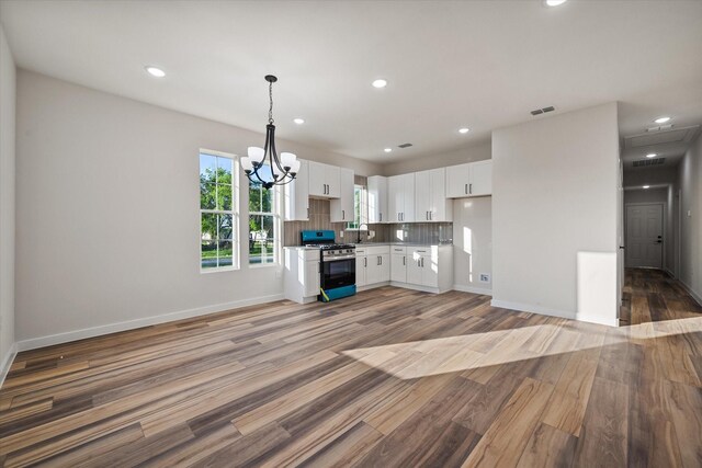 kitchen featuring stainless steel range with gas stovetop, white cabinetry, a chandelier, light wood finished floors, and recessed lighting