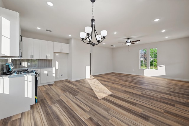 kitchen featuring ceiling fan, white cabinets, wood finished floors, pendant lighting, and a chandelier