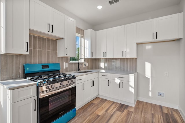 kitchen with gas range, a sink, light countertops, backsplash, and recessed lighting