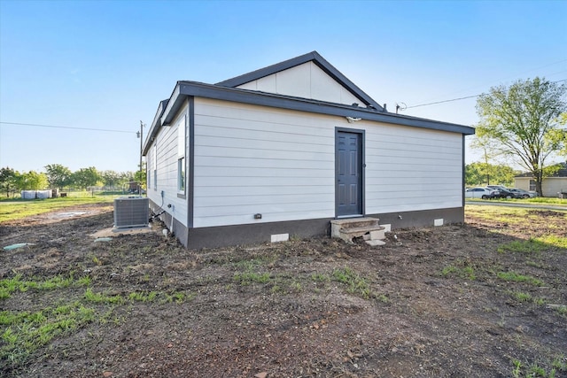 rear view of property featuring entry steps, cooling unit, board and batten siding, and crawl space