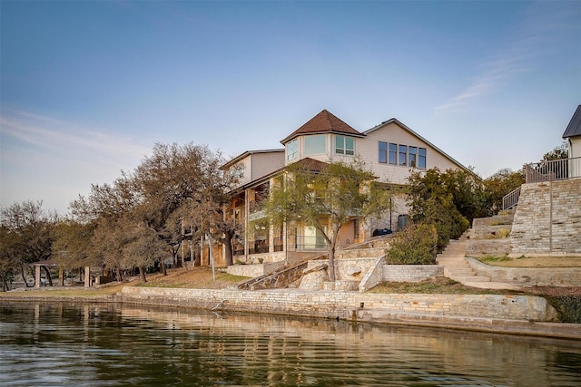 rear view of property with a water view and stairway