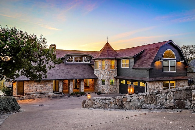 view of front of property featuring a garage, aphalt driveway, and stone siding