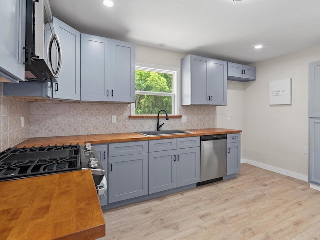 5134 Anderson Cir, Garland, TX 75043 - kitchen with butcher block countertops, appliances with stainless steel finishes, a sink, light wood-style floors, and recessed lighting
