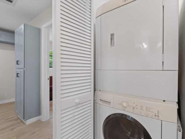 5134 Anderson Cir, Garland, TX 75043 - laundry room with stacked washer and clothes dryer, light wood-style flooring, and baseboards