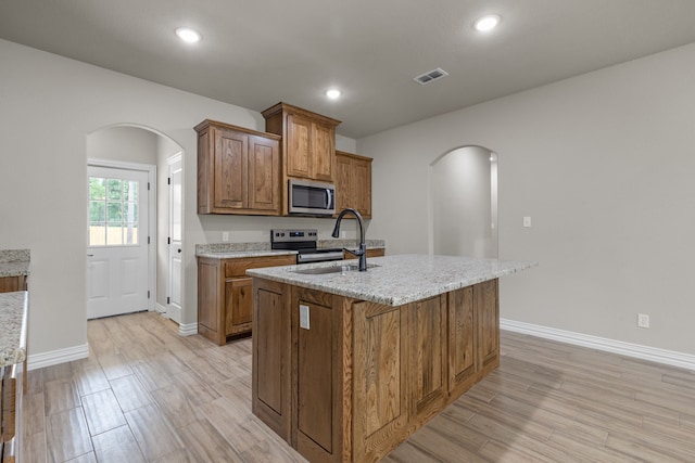 2685 Thompson Rd, Weatherford, TX 76087 - kitchen featuring arched walkways, stainless steel appliances, brown cabinets, baseboards, and recessed lighting