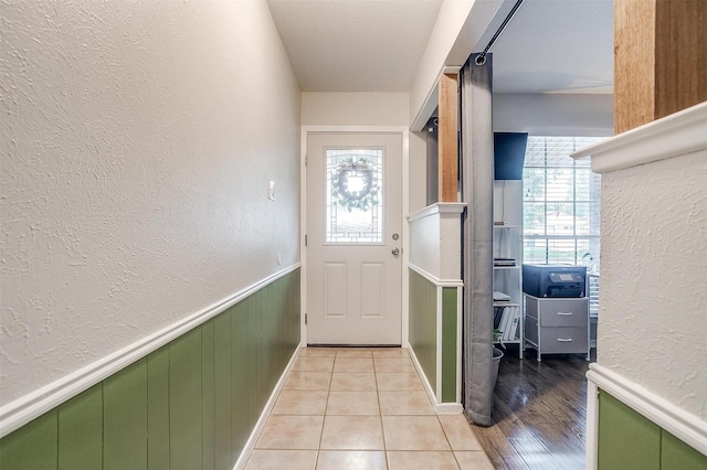 136 NW Suzanne Ter, Burleson, TX 76028 - doorway to outside featuring a textured wall, light tile patterned flooring, and wainscoting