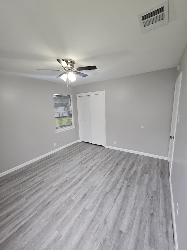spare room with baseboards, visible vents, a ceiling fan, and wood finished floors