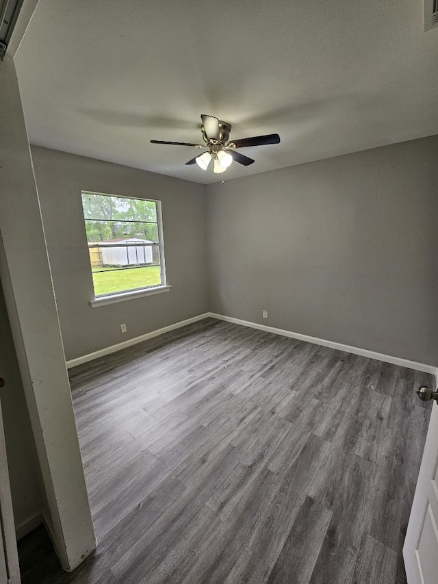 spare room with baseboards, dark wood-style flooring, ceiling fan, and visible vents