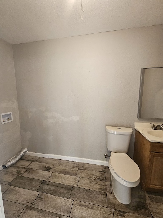 half bathroom featuring toilet, vanity, baseboards, and wood tiled floor
