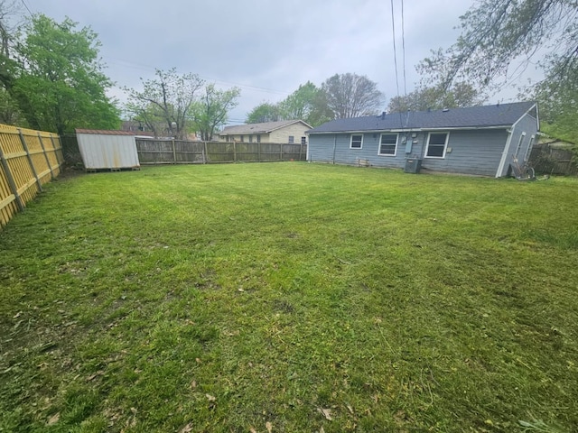 view of yard with an outbuilding, a fenced backyard, and a shed