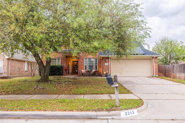 view of front facade with brick siding, a garage, driveway, and fence