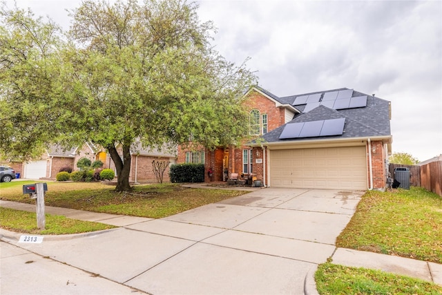 view of front of property with brick siding, a garage, roof mounted solar panels, and driveway