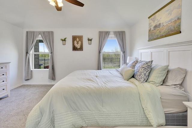 carpeted bedroom featuring multiple windows, vaulted ceiling, baseboards, and ceiling fan