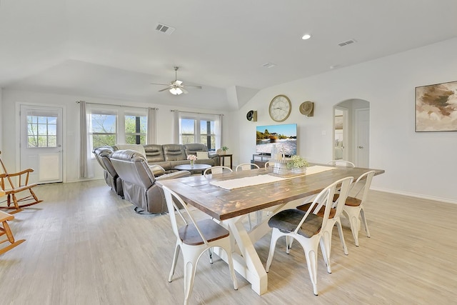 dining space featuring vaulted ceiling, arched walkways, light wood-style floors, ceiling fan, and baseboards