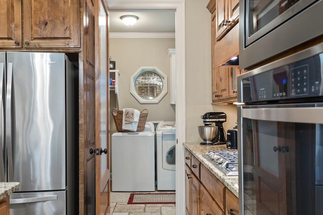 washroom with separate washer and dryer, ornamental molding, and laundry area