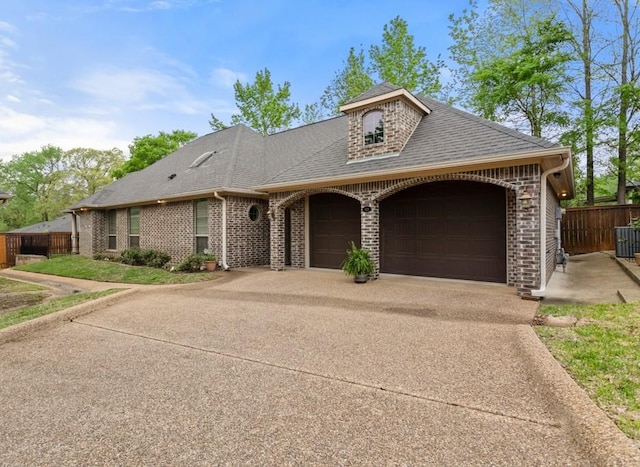 view of front of home with fence, driveway, brick siding, and a garage